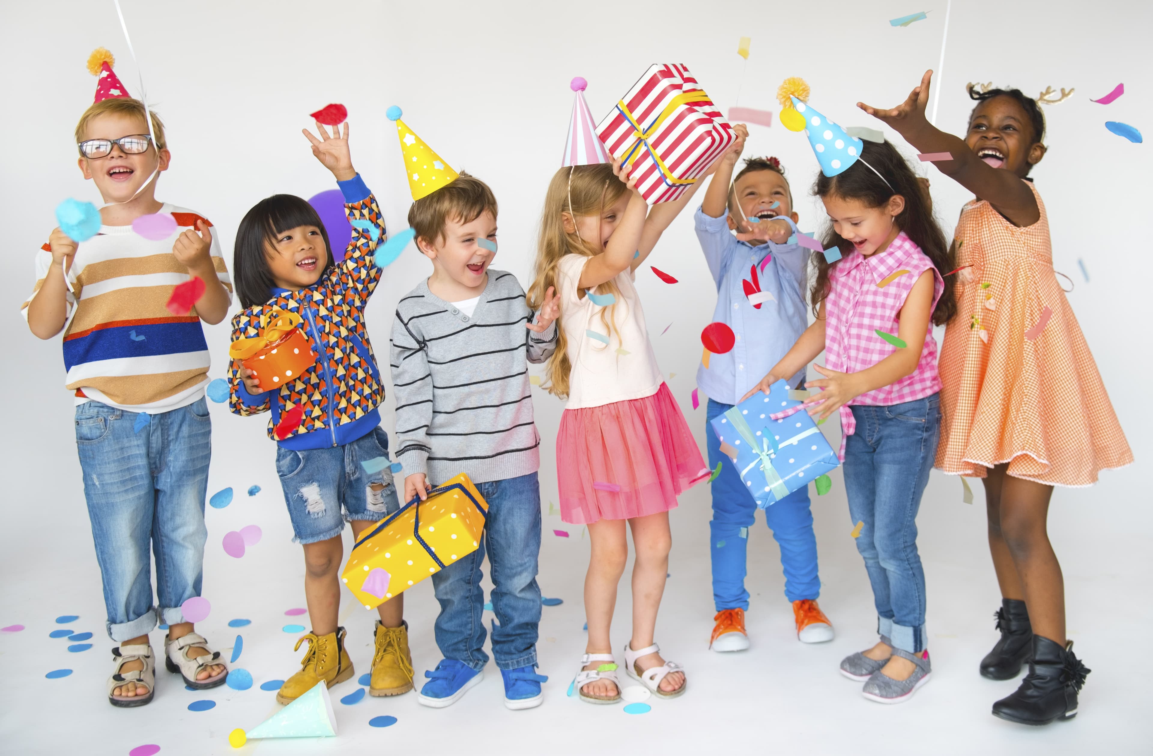 Children celebrating a birthday with colorful balloons and party hats